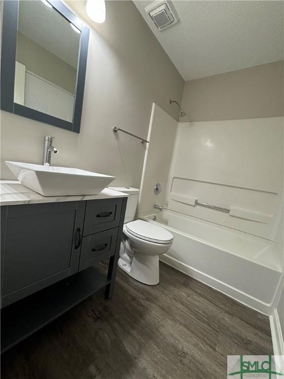 full bathroom with shower / bathtub combination, wood-type flooring, toilet, and vanity