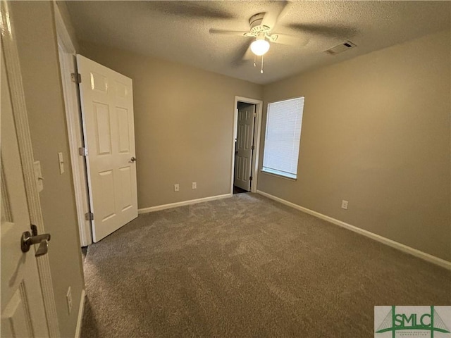 empty room with dark colored carpet, ceiling fan, and a textured ceiling