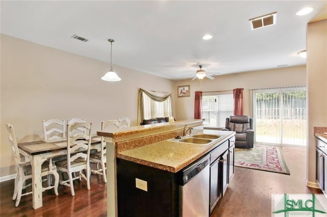 kitchen featuring stainless steel dishwasher, hanging light fixtures, sink, dark wood-type flooring, and a kitchen island with sink