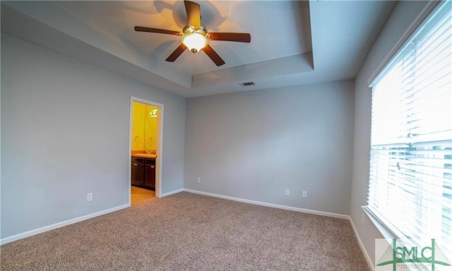 carpeted empty room featuring ceiling fan and a tray ceiling