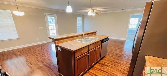 kitchen featuring sink, a kitchen island with sink, hanging light fixtures, and crown molding