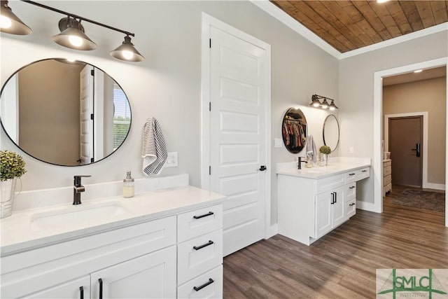 full bath featuring wood finished floors, two vanities, a sink, crown molding, and wooden ceiling