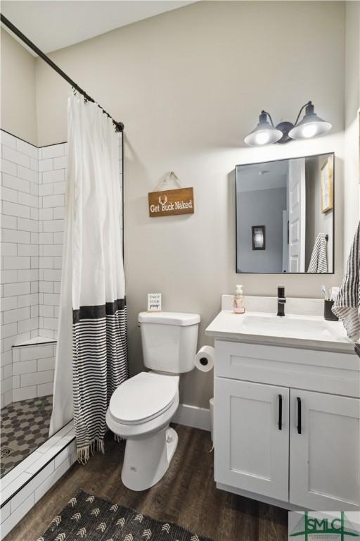 bathroom featuring vanity, wood finished floors, a stall shower, a baseboard heating unit, and toilet