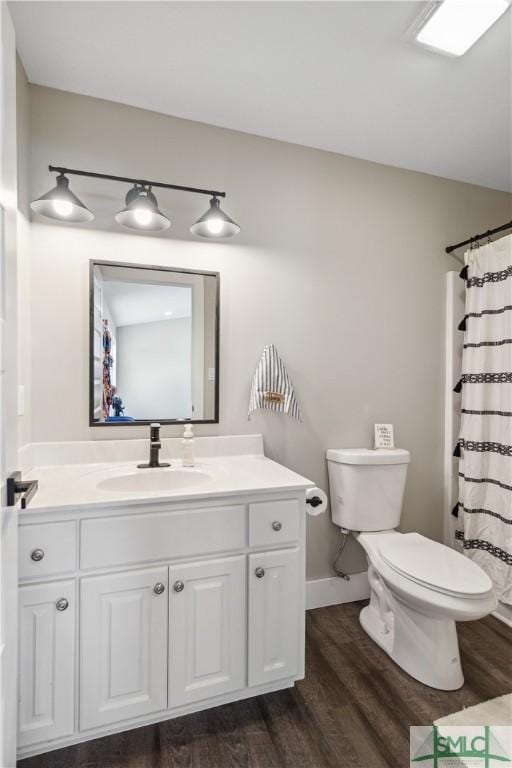 bathroom with hardwood / wood-style floors, toilet, walk in shower, and vanity