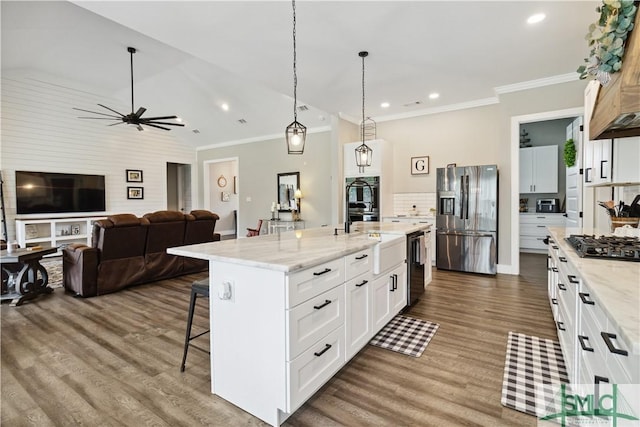 kitchen with white cabinets, stainless steel appliances, backsplash, hanging light fixtures, and a kitchen island with sink