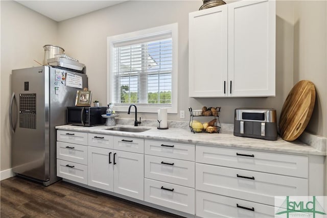 kitchen featuring sink, white cabinetry, stainless steel fridge, and light stone countertops