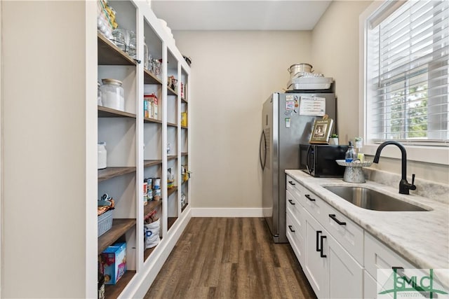 kitchen featuring sink, white cabinets, dark wood-type flooring, and light stone countertops