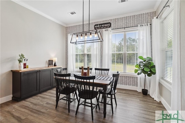 dining room featuring baseboards, wood finished floors, visible vents, and ornamental molding