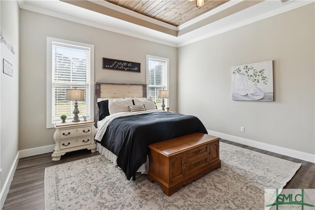 bedroom featuring baseboards, crown molding, a tray ceiling, and wood finished floors