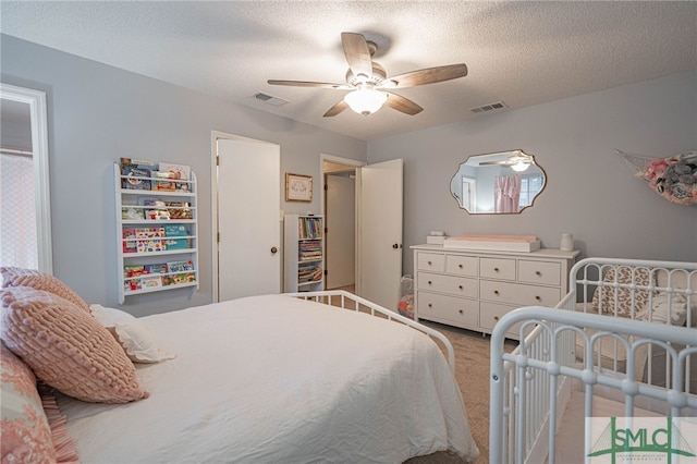 carpeted bedroom featuring ceiling fan and a textured ceiling