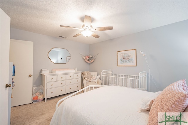 bedroom with ceiling fan, a textured ceiling, and light carpet