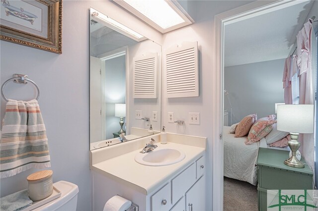 bathroom with toilet, vanity, and a skylight