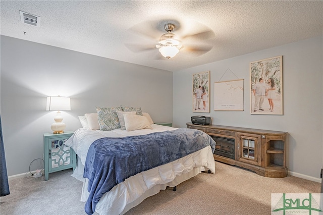 carpeted bedroom featuring ceiling fan and a textured ceiling