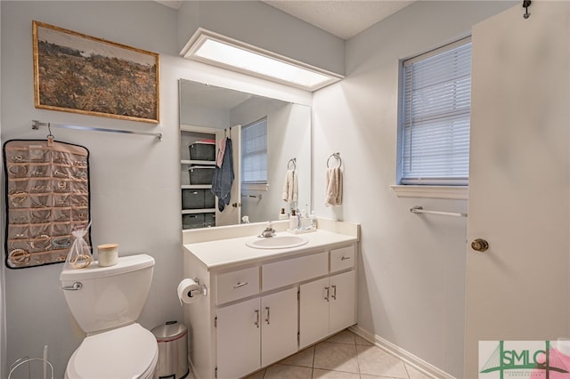 bathroom with tile patterned floors, vanity, a skylight, and toilet