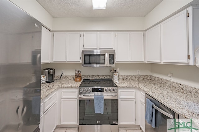 kitchen with stainless steel appliances, white cabinetry, and a textured ceiling