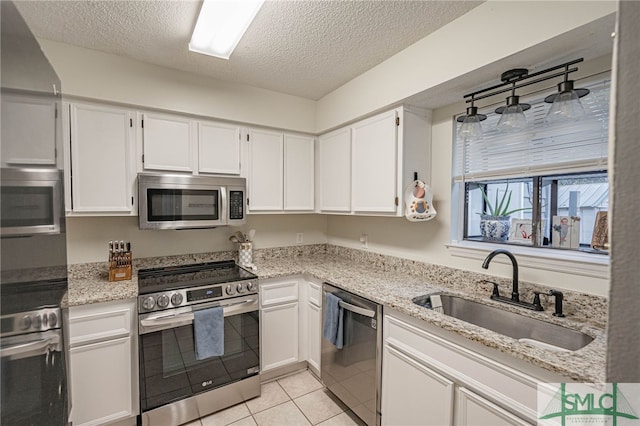 kitchen featuring white cabinets, stainless steel appliances, light tile patterned flooring, and sink