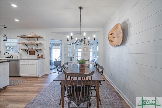 dining space featuring light wood-type flooring, a notable chandelier, and sink