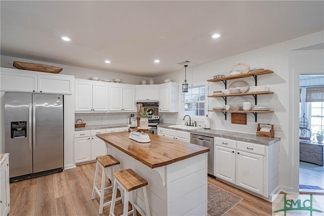 kitchen with white cabinets, appliances with stainless steel finishes, sink, and a kitchen island