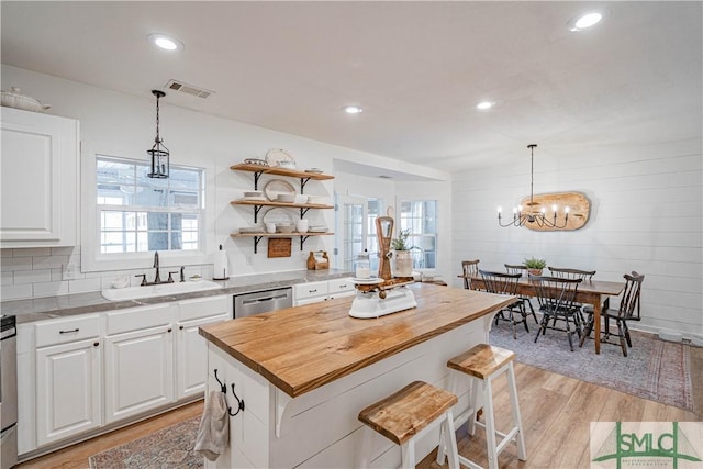 kitchen with pendant lighting, white cabinets, dishwasher, a center island, and sink