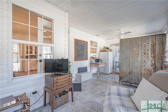 interior space featuring ceiling fan and wooden walls