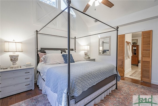 bedroom featuring ceiling fan, dark wood-type flooring, ensuite bathroom, and vaulted ceiling