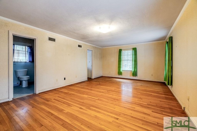 spare room featuring light wood-type flooring and crown molding