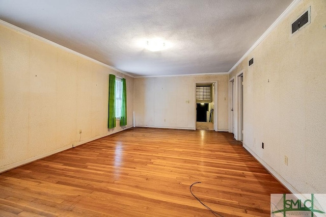 spare room featuring light hardwood / wood-style flooring, a textured ceiling, and crown molding