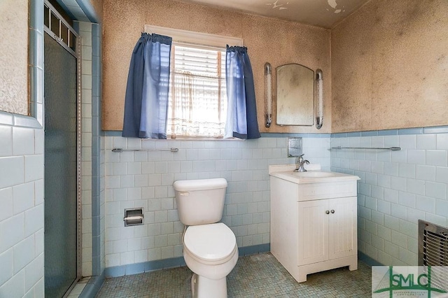 bathroom with tile patterned flooring, an enclosed shower, tile walls, toilet, and vanity