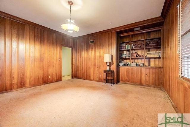 carpeted empty room with wood walls and crown molding