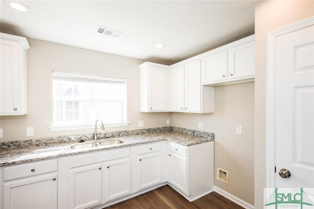 kitchen with light stone countertops, visible vents, a sink, and white cabinetry