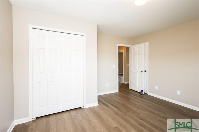 unfurnished bedroom with a closet, baseboards, and wood finished floors