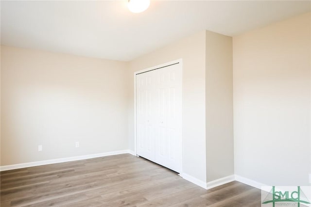 unfurnished bedroom with a closet, baseboards, and wood finished floors