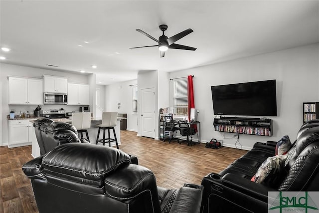 living room featuring dark wood-type flooring and ceiling fan