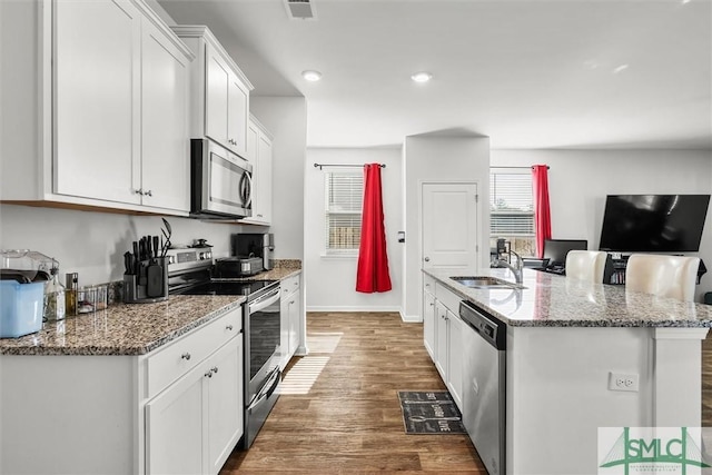 kitchen with sink, white cabinetry, a center island with sink, appliances with stainless steel finishes, and stone counters