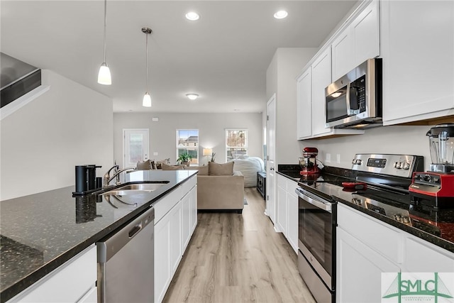 kitchen featuring pendant lighting, white cabinetry, stainless steel appliances, dark stone counters, and sink