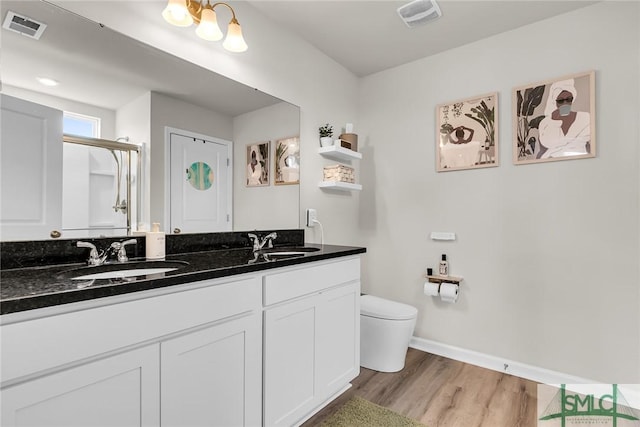 bathroom with vanity, hardwood / wood-style flooring, a shower with door, and toilet