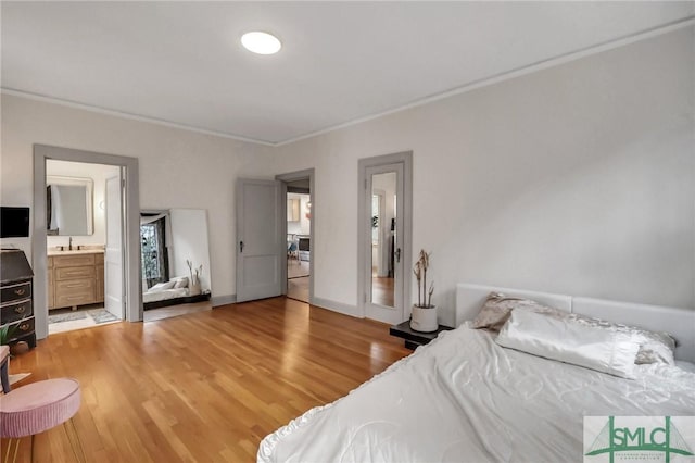 bedroom featuring hardwood / wood-style floors, crown molding, and ensuite bath