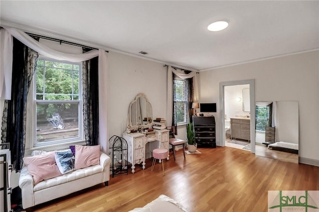 living area with light hardwood / wood-style flooring and ornamental molding