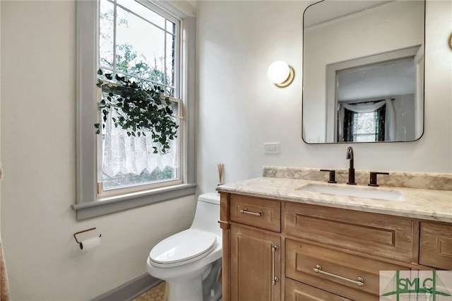 bathroom featuring plenty of natural light, toilet, and vanity