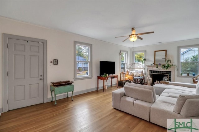 living room featuring light wood-type flooring, a wealth of natural light, and a tiled fireplace