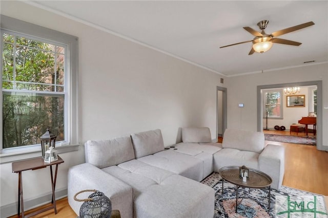 living room featuring ceiling fan with notable chandelier, crown molding, and wood-type flooring