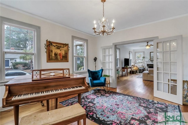 misc room with ceiling fan with notable chandelier, hardwood / wood-style floors, crown molding, and a healthy amount of sunlight