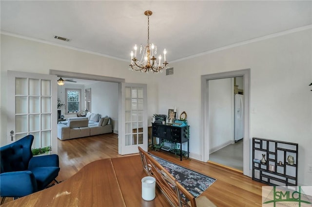 dining room featuring wood-type flooring, crown molding, and french doors