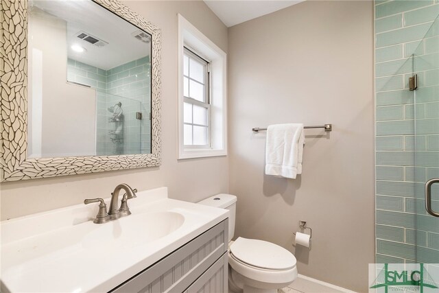 bathroom with a shower with shower door, toilet, and vanity