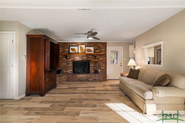 living room featuring ceiling fan, light hardwood / wood-style floors, and a brick fireplace