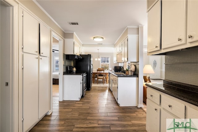 kitchen featuring dark hardwood / wood-style flooring, stainless steel stove, tasteful backsplash, white cabinets, and exhaust hood