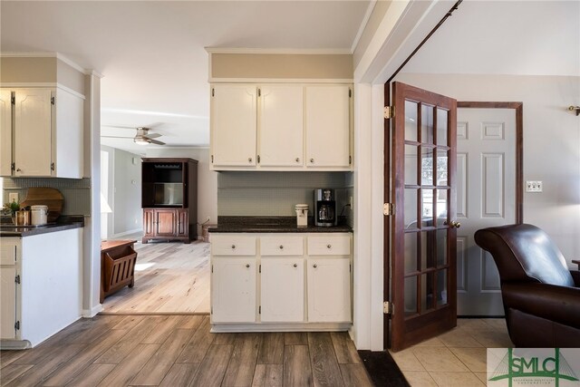 kitchen featuring white cabinetry, light hardwood / wood-style floors, backsplash, ceiling fan, and crown molding