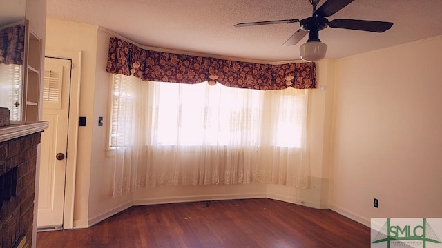 spare room featuring ceiling fan, dark wood-type flooring, a textured ceiling, and a fireplace