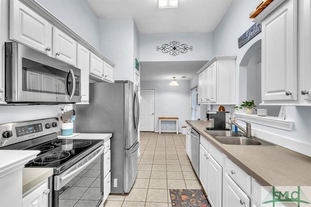 kitchen with stainless steel appliances, sink, light tile patterned floors, and white cabinets