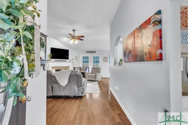 living room featuring ceiling fan, lofted ceiling, wood-type flooring, and a textured ceiling